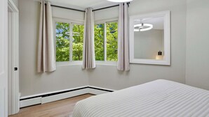 Un dormitorio con cama, ventana con cortinas, ventilador de techo e iluminación en la pared.