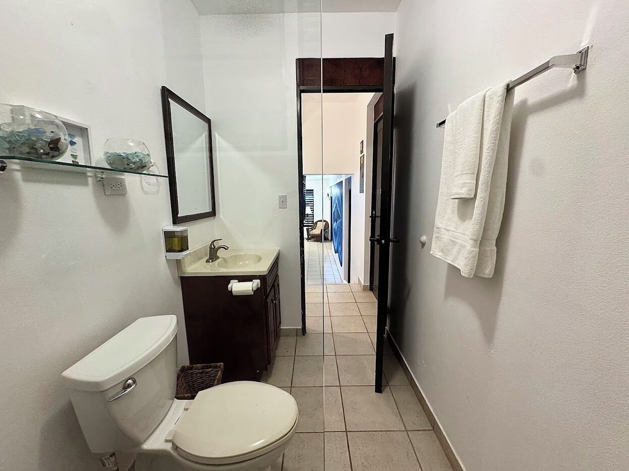 A bathroom with a toilet, sink, and mirror.