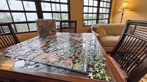 A puzzle on a glass table in a room with large windows, a sofa, and a lamp. - Vieques BioBay B&B,The Turtle Room:Sleep Under the Stars, Paddle the Glowing Bay (Vieques)