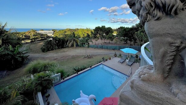 A pool with a lion statue, a clear sky, and a view of the ocean. - Vieques BioBay B&B,The Turtle Room:Sleep Under the Stars, Paddle the Glowing Bay (Vieques)