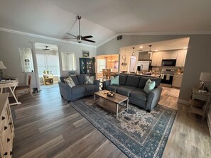 Ein geräumiges Wohnzimmer mit einem großen grauen Sofa, einem Couchtisch und einem gemusterten Teppich.