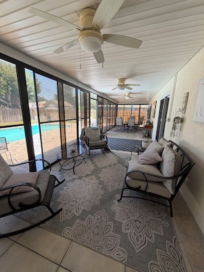 Eine überdachte Terrasse mit Pool, Schaukelstühlen und Essbereich.