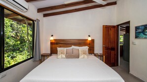 Quarto com cama, cabeceira de madeira, abajures, janela com cortinas e ar condicionado.