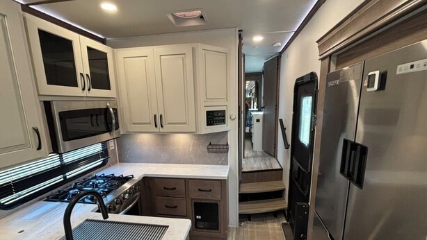 A compact kitchen with a gas stove, microwave, and stainless steel refrigerator. - Unique Country Getaway Luxury Peaceful & Spacious (Cleveland)