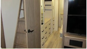 A room with a wooden ladder, a closet with multiple drawers, and a television on a stand. - Unique Country Getaway Luxury Peaceful & Spacious (Cleveland)