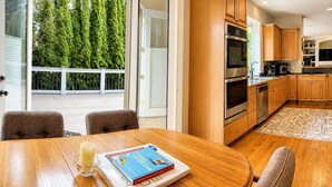Una cucina moderna con mobili in legno, elettrodomestici in acciaio inossidabile e un'area pranzo con tavolo e sedie in legno.