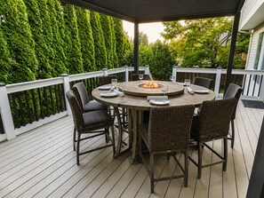 A covered outdoor patio with a round table, wicker chairs, and a fire feature. - 5.0 Star Upscale and Spacious Home with Gym+Theater+Central AC+More” (Bothell)