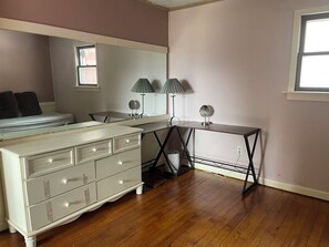 A bedroom with a bed, dresser, desk, lamp, mirror, and window. - Lovely 2-bedroom cottage in Fletcher perfect for a relaxing getaway (Fletcher)
