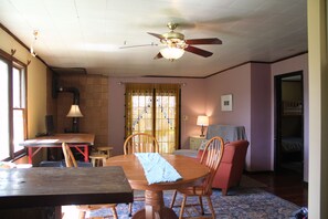 A dining area with a wooden table, chairs, a ceiling fan, and a window with curtains. - Lovely 2-bedroom cottage in Fletcher perfect for a relaxing getaway (Fletcher)