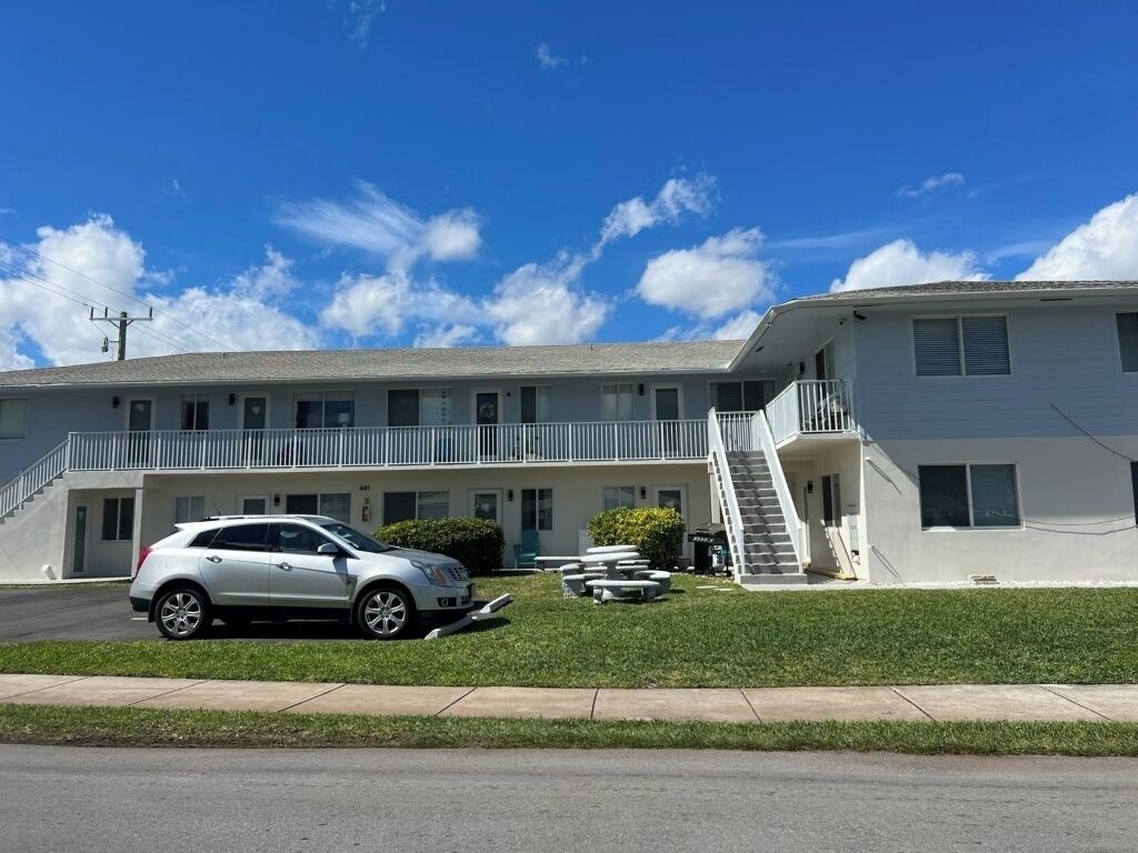A two-story motel with a white exterior, a covered front porch, and a staircase leading to the second floor.