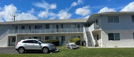 A two-story motel with a white exterior, a covered front porch, and a staircase leading to the second floor.