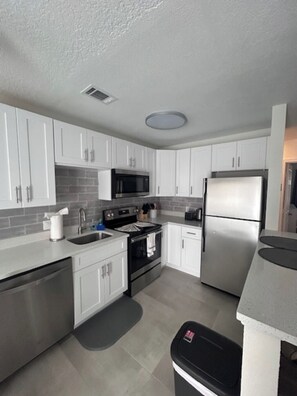 A modern kitchen with white cabinets, stainless steel appliances, and a grey countertop.