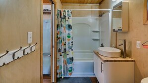 Ein Badezimmer mit Dusche, Waschbecken, Spiegel und Handtuchhalter.