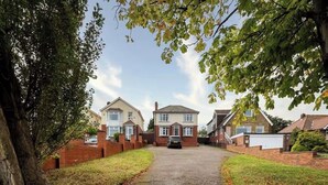 A residential street with houses, a driveway, and a large tree. - Large detached home for families and group stays (Hoyland)