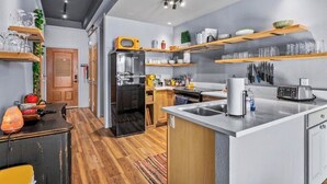 Eine moderne Küche mit Kühlschrank, Herd und Holzregalen.