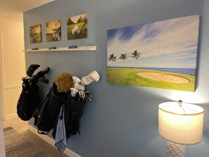 Ein Zimmer mit Wandbild zum Thema Golf, einer Lampe und einem Kleiderhaken mit Taschen.