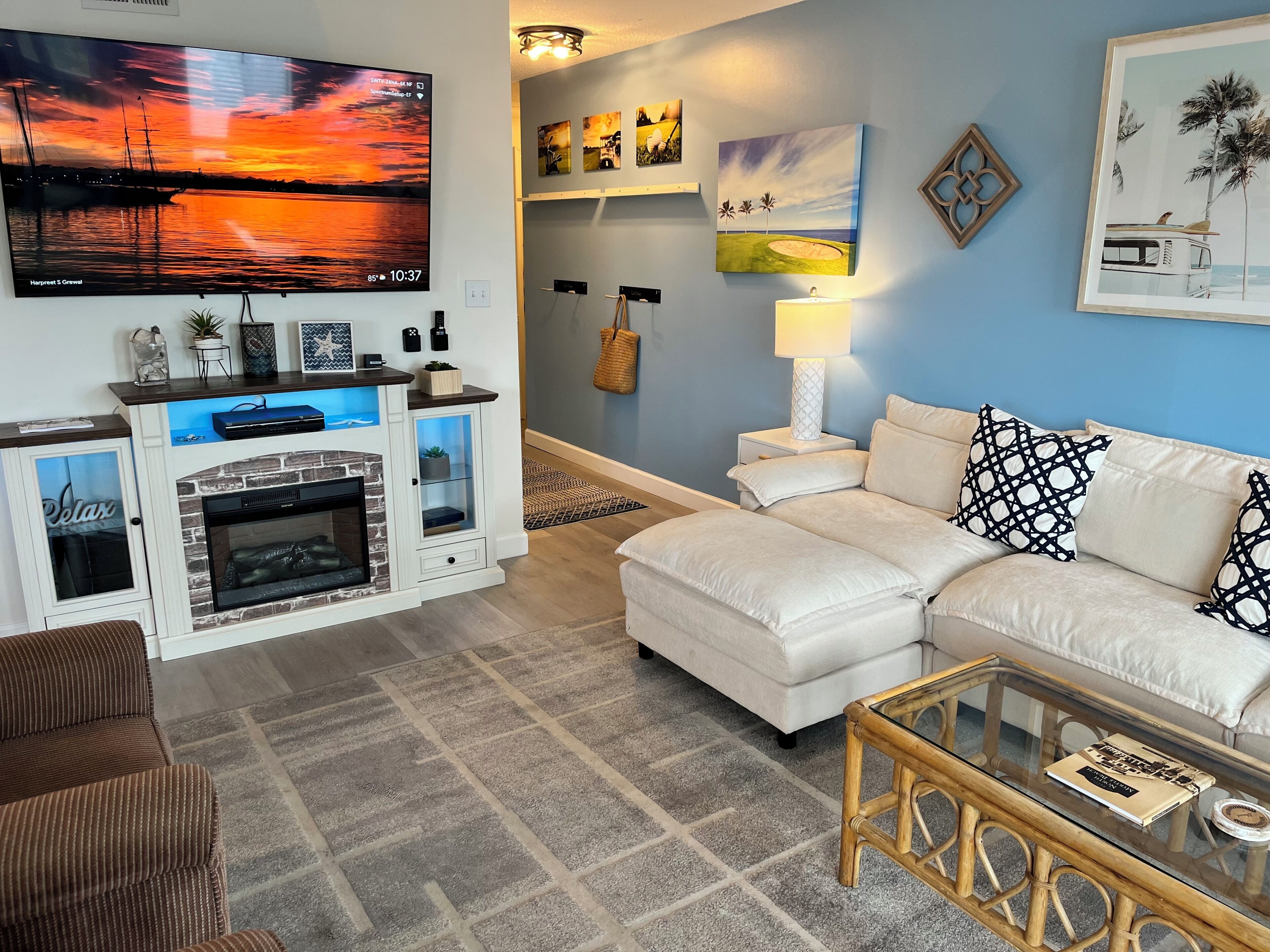 A living room with a fireplace, a sofa, a glass coffee table, and wall art.
