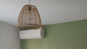 A room with a grey sofa, a small round table, a white cabinet, and a hanging light fixture.