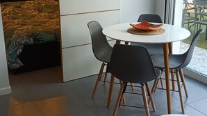 A modern dining area with a round table, black chairs, and a woven ceiling light fixture.