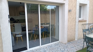 A sliding glass door leading to a kitchen with a dining area, a small table, and a chair.
