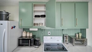 A kitchen with green cabinets, a microwave, a stove, and a toaster.