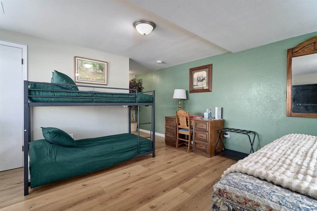 Una habitación con literas, un escritorio, una silla, una lámpara y una cama.