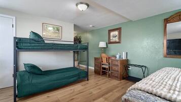 Una habitación con literas, un escritorio, una silla, una lámpara y una cama.