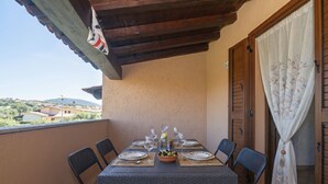 Een balkon met een tafel voor vier personen, stoelen, een houten plafond en uitzicht op het landschap.