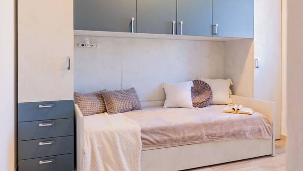 Een slaapkamer met een bed, een dressoir en een kledingkast.