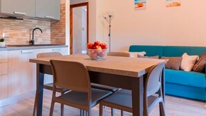Een moderne keuken met een eettafel, stoelen en een schaal fruit.