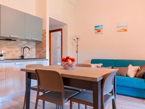 A modern kitchen with a dining table, chairs, and a bowl of fruit. - Perla San Teo by Interhome (San Teodoro)