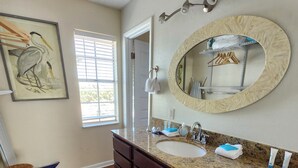 A bathroom with a granite countertop, double sink, wooden vanity, and a large mirror.