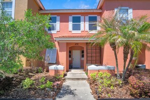 A two-story house with a red exterior, white shutters, and a number '4741' on the front door. - Minutes to Disney! Gated 3BR Resort Townhome (Kissimmee)