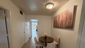 A hallway with a dining area featuring a round table and four chairs, a ceiling light, and a wooden accent wall.
