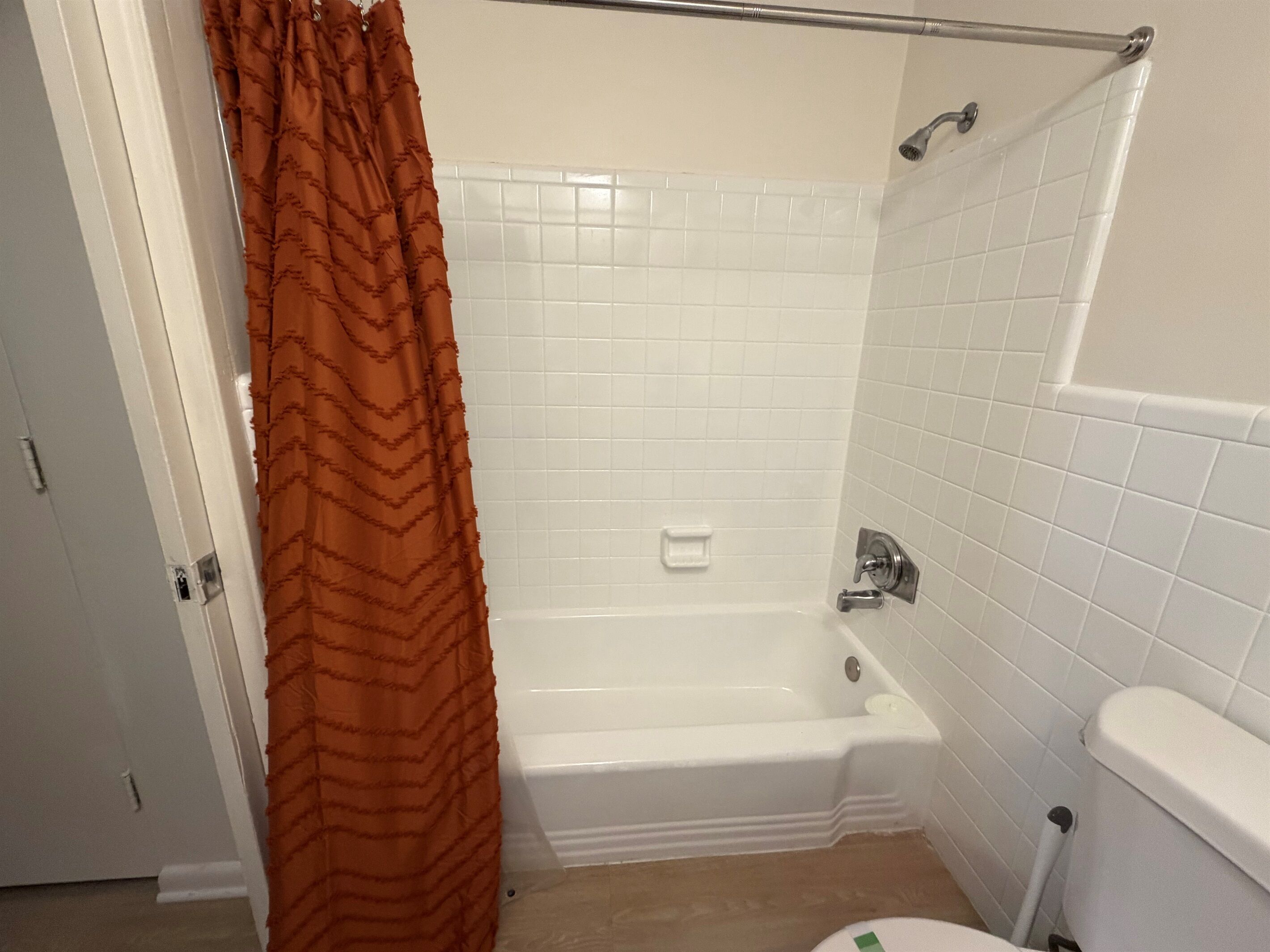 A bathroom with a white bathtub, a shower, and a toilet.