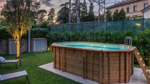 A wooden hot tub in a backyard with a grassy lawn, a wooden deck, and a fence. - Charming Lucca Villa With Garden (Lucca)
