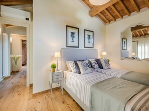 Ein Schlafzimmer mit einem Doppelbett, zwei Nachttischen, einem Schminktisch und gerahmten Bildern an der Wand.