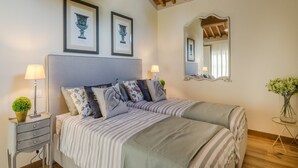 A bedroom with a double bed, bedside tables, a mirror, and framed artwork on the wall. - Charming Lucca Villa With Garden (Lucca)
