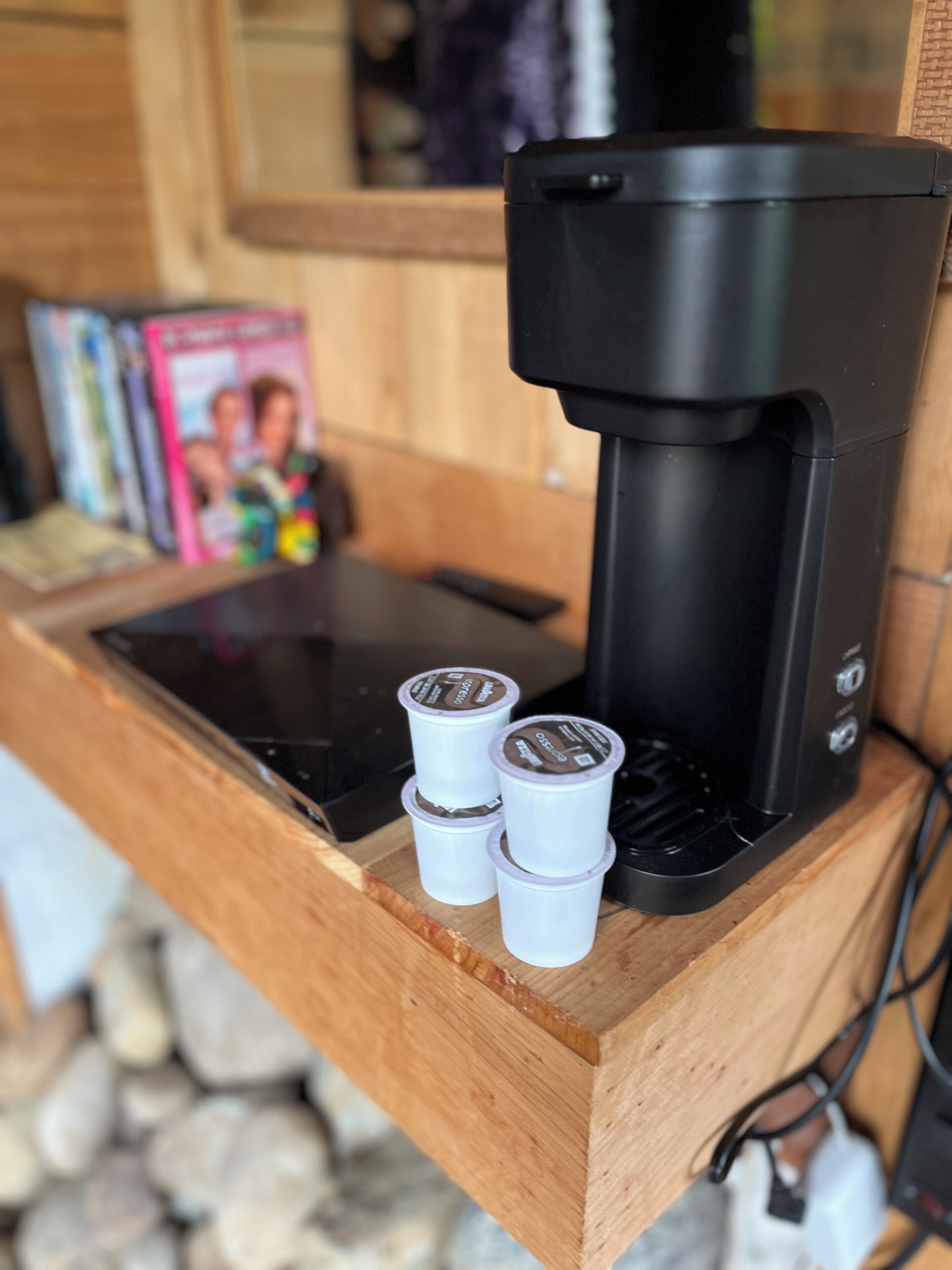 A coffee maker with four coffee pods on a wooden counter.