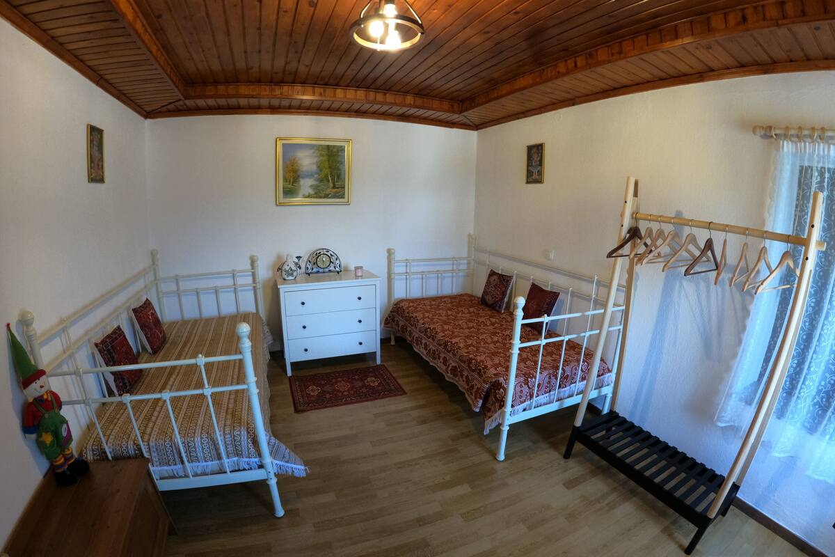 Une chambre avec deux lits, une commode, un portant à vêtements et un tableau au mur.