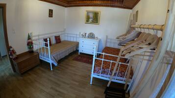 Een kamer met twee bedden, een dressoir, een houten plafond en een schilderij aan de muur.