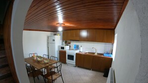 A kitchen with wooden cabinets, a dining table with chairs, a refrigerator, a microwave, and a stove.