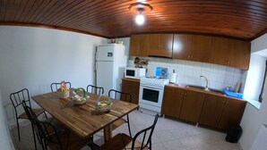 A kitchen with wooden cabinets, a dining table with chairs, a refrigerator, an oven, and a microwave.