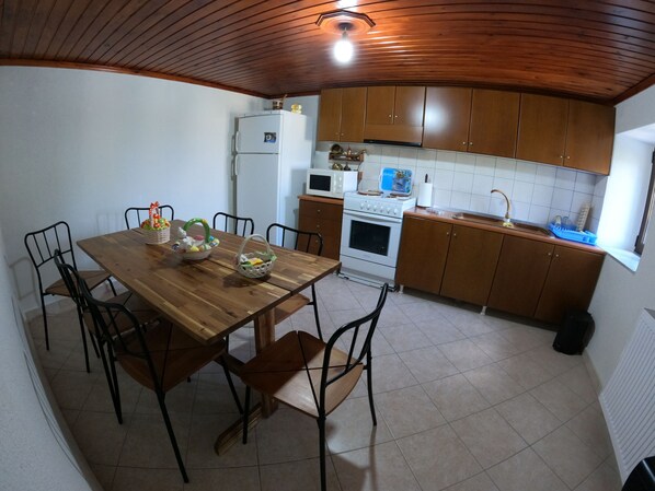 A kitchen with wooden cabinets, a dining table with chairs, a refrigerator, an oven, and a microwave.