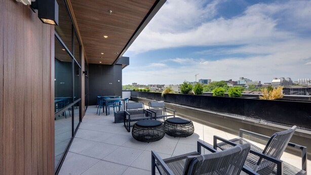 Eine Dachterrasse mit Sitzgelegenheiten im Freien, Blick auf die Stadt und einem modernen architektonischen Design.