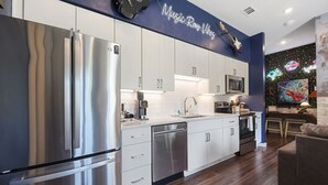 Eine moderne Küche mit Edelstahlgeräten, weißen Schränken und einem Neonlichtschild mit der Aufschrift 'Music Row Vibes'.