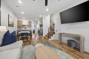 A modern living room with a sofa, a dining area, a kitchen, and a staircase. - Curated West Nash Escape | 10 Min to Broadway (Nashville)
