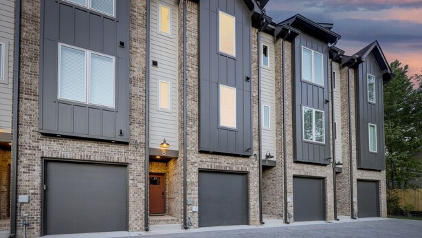 A multi-story building with a brick facade, large garage doors, and a well-maintained driveway. - Curated West Nash Escape | 10 Min to Broadway (Nashville)