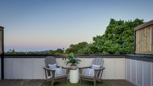 A deck with two Adirondack chairs, a small table, and a potted plant. - Curated West Nash Escape | 10 Min to Broadway (Nashville)