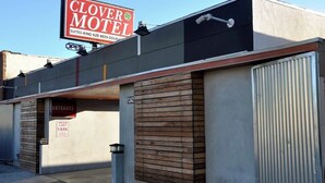 Un motel con un letrero que anuncia 'Clover Motel', con suites, camas tamaño king y habitaciones dobles.